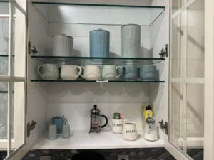 A shelf with cups and coffee pots on it.