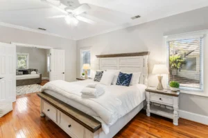 A bedroom with white furniture and wooden floors.