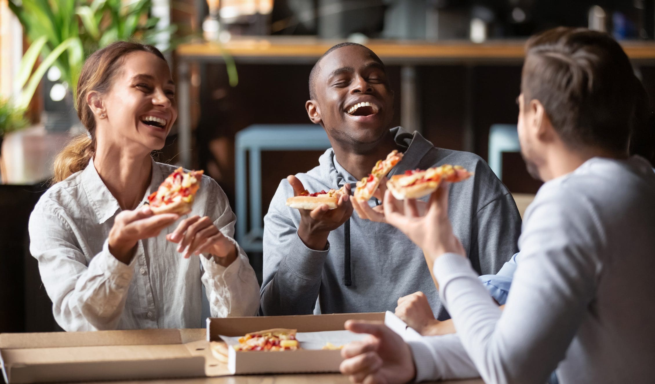A group of people sitting around eating pizza.