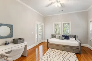 A bedroom with a bed, desk and window.