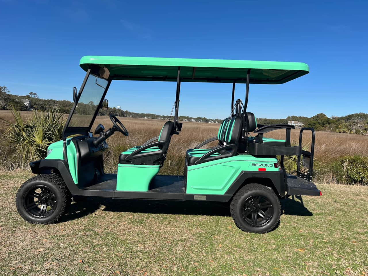 A green golf cart is parked in the grass.