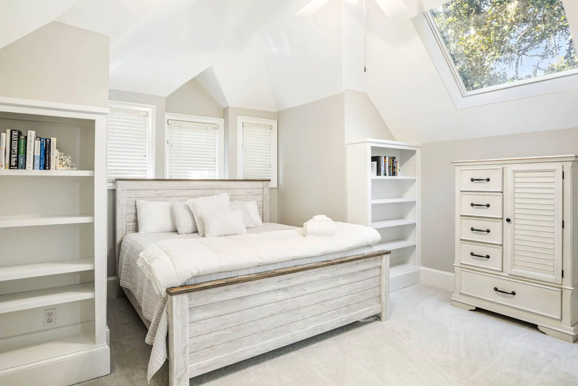 A white bedroom with a large bed and dresser.
