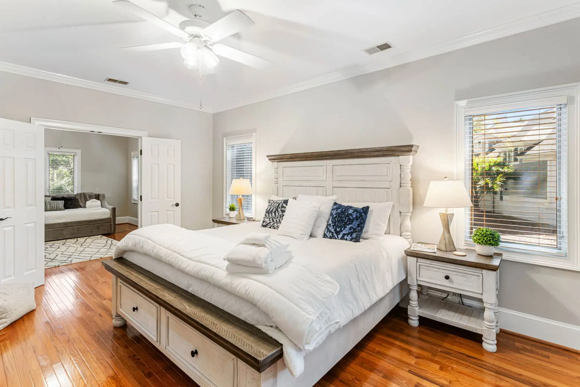 A bedroom with white furniture and wooden floors.