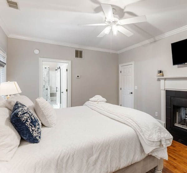 A bedroom with a bed, fireplace and television.