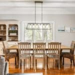 A dining room table with chairs and lights above it.