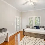 A bedroom with a bed, desk and window.