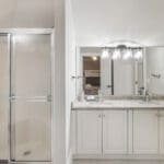 A bathroom with white cabinets and a shower.