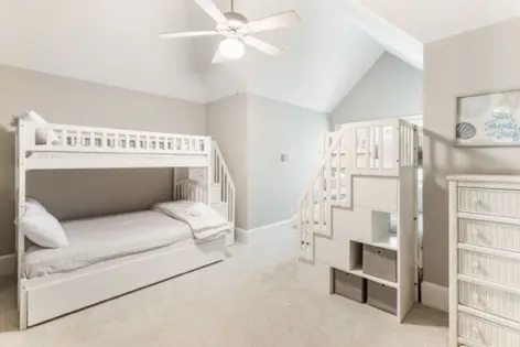 A bedroom with two bunk beds and stairs.
