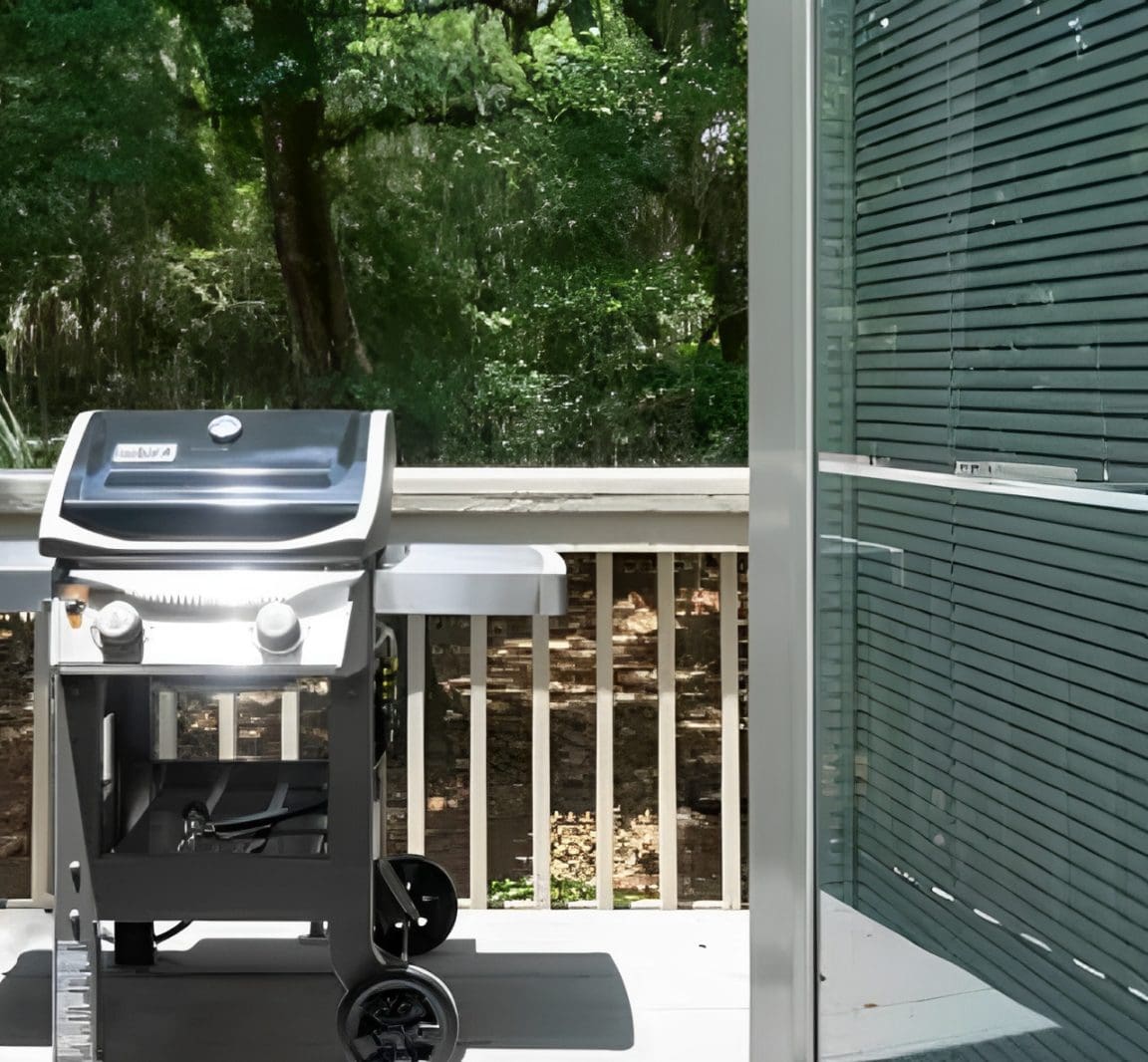 A grill on the back deck of a house.