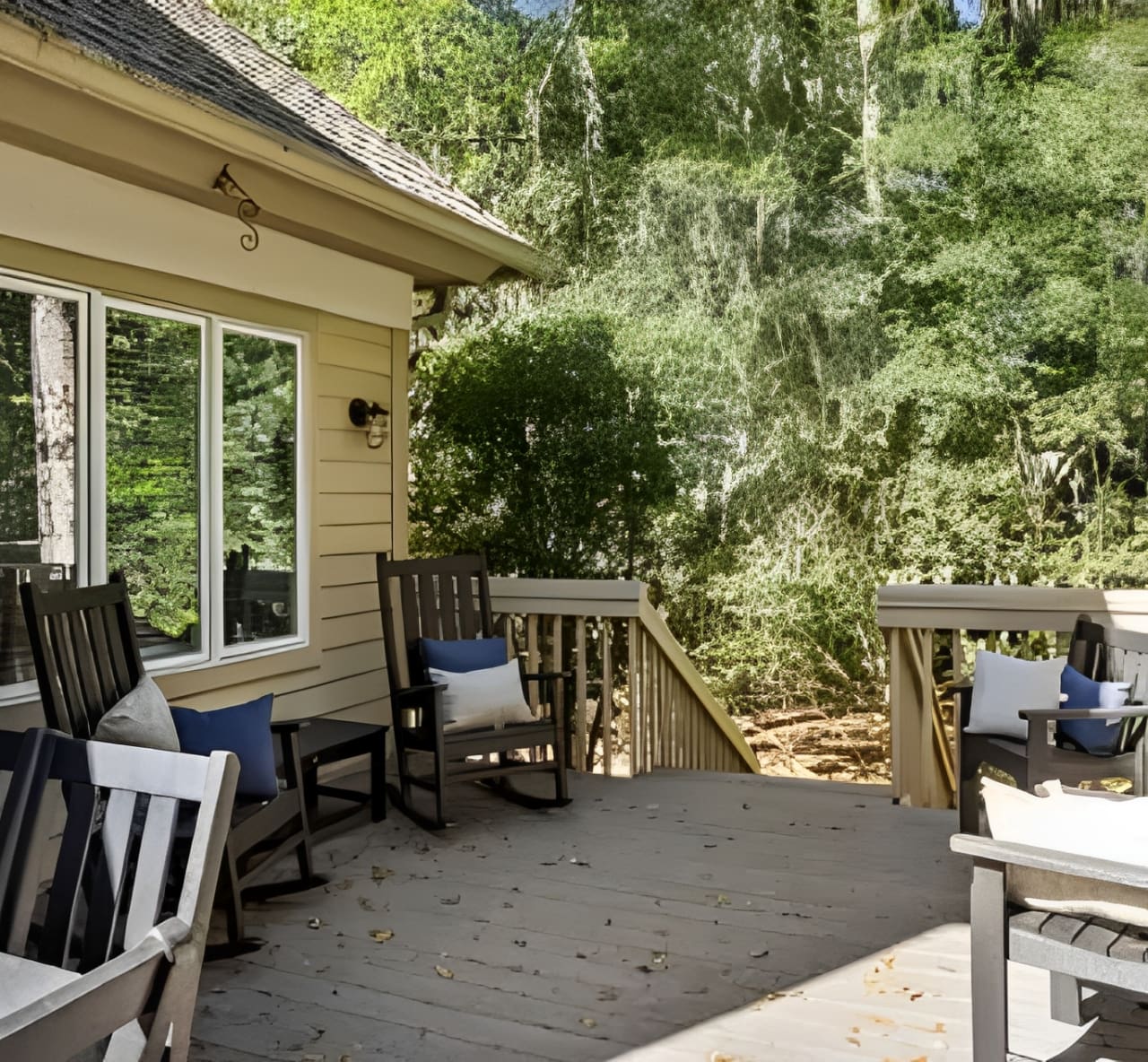 A porch with several rocking chairs and tables.